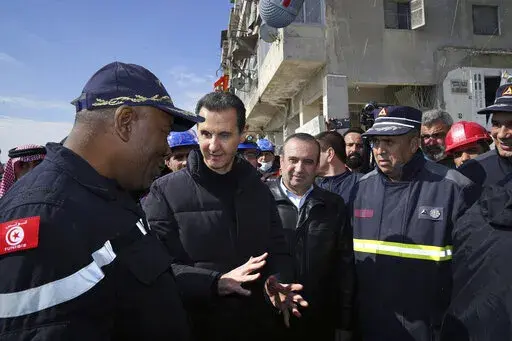 In this photo released by the official Syrian state news agency SANA, Syrian President Bashar Assad, second left, speaks with an Algerian rescue team at the site of destroyed buildings fallowing devastating earthquake, in Aleppo province, Syria, Friday, Feb. 10, 2023. Rescuers pulled several people alive from the shattered remnants of buildings on Friday, some who survived more than 100 hours trapped under crushed concrete in the bitter cold after a catastrophic earthquake slammed Turkey and Syr