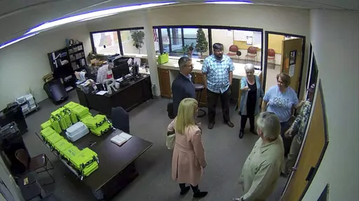 This Jan. 7, 2021, image taken from Coffee County, Ga., security video, appears to show Cathy Latham (center, long turquoise top), introducing members of a computer forensic team to local election officials. Latham was the county Republican Party chair at the time. The computer forensics team was at the county elections office in Douglas, Ga., to make copies of voting equipment in an effort that documents show was arranged by attorney Sidney Powell and others allied with then-President Donald Tr