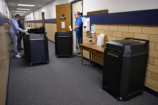 Christopher Prue, president of the Registrars of Voters Association of Connecticut, right, moves new voting tabulators out of his office at the Registrars of Voters to be redistributed to other towns, Thursday, March 27, 2025, in Vernon, Conn. (AP Photo/Jessica Hill)