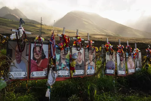 Photos of victims are displayed under white crosses at a memorial for victims of the August 2023 wildfire, above the Lahaina Bypass highway, Dec. 6, 2023, in Lahaina, Hawaii. Hawaii officials said Friday, Jan. 26, 2024, that they have identified the last of the 100 known victims of the wildfire that destroyed Lahaina in August of last year. (AP Photo/Lindsey Wasson, File)