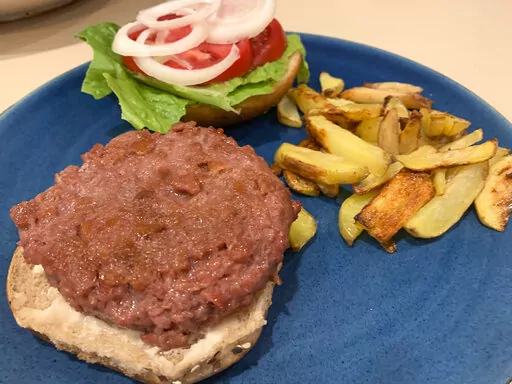A Beyond Burger, made with lettuce, tomato and onion, is plated with a side of potato fries at a home in Westchester County, N.Y. on Jan. 10, 2022. Plant-based meat products aim to imitate meat in taste, texture, appearance and smell, and the likenesses are now pretty impressive. They can also be used in pasta sauces, stir fries and casseroles. (AP Photo/Julia Rubin)