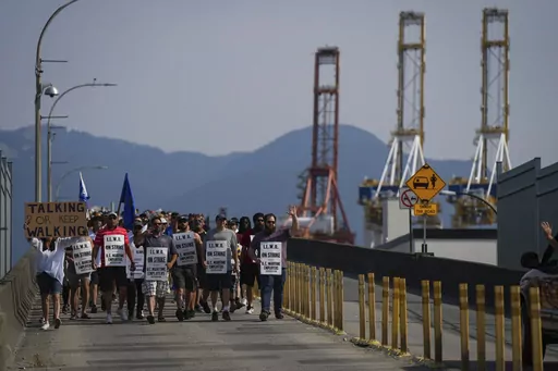 Striking International Longshore and Warehouse Union Canada workers march to a rally as gantry cranes used to load and unload cargo containers from ships sit idle at port, in Vancouver, on Thursday, July 6, 2023. (Darryl Dyck /The Canadian Press via AP)