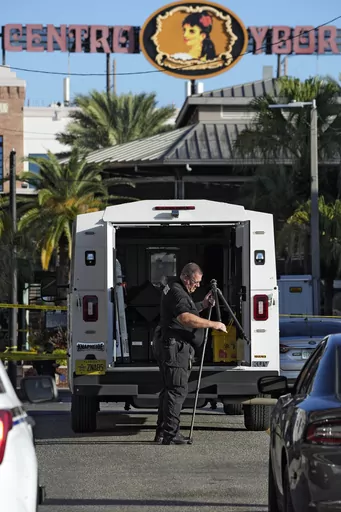 A Tampa police officer opens a tripod in the Ybor City section of Tampa, Fla., after a shooting early Sunday, Oct. 29, 2023. A fight between two groups turned deadly in a shooting during Halloween festivities. (AP Photo/Chris O'Meara)