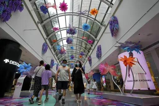 Residents wearing face masks walk through the reopening shopping mall decorated with colorful flowers after being closed due to COVID-19 restrictions in Beijing, Sunday, May 29, 2022. (AP Photo/Andy Wong)