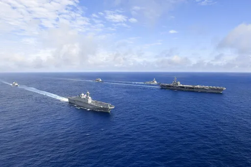In this photo provided by South Korea's Defense Ministry, U.S. nuclear-powered aircraft carrier USS Ronald Reagan, right, and South Korea's landing platform helicopter (LPH) ship Marado, second from left, sail during a joint military exercise at an undisclosed location, Saturday, June 4, 2022. (South Korea Defense Ministry via AP)
