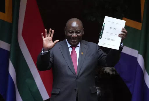FILE — South African President Cyril Ramaphosa shows the signed bill for National Health Insurance signed into law in Pretoria, South Africa, Wednesday, May 15, 2024. Several polls have the African National Congress' support below 50% ahead of next Wednesday's, May 29, 2024 vote, raising the prospect that it might not be the majority party for the first time since Nelson Mandela led it to victory in the first all-race elections that ended white minority rule in 1994. (AP Photo/Themba Hadebe, F
