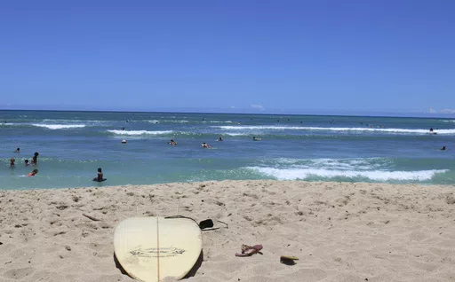 A surfboard lies on the sand on the sand at a beach known as White Plains in Ewa Beach, Hawaii, May 12, 2023. A judge has halted plans for an artificial wave pool until developers can revise an environmental assessment to address concerns raised by Native Hawaiians and others who say the project is unnecessary in the birthplace of surfing and a waste of water. (AP Photo/Jennifer Sinco Kelleher, File)