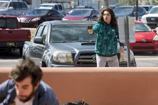 A man who identified himself to the Albuquerque Journal as Ryan Martinez, of East Mountains, pulls a gun during a rally outside the Rio Arriba County building in Española, N.M., Thursday, Sept. 28, 2023. The man scrambling at lower left was not shot. (Eddie Moore/Albuquerque Journal via AP)