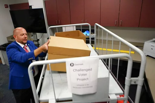 Gwinnett County elections supervisor Zach Manifold looks over boxes of voter challenges on Thursday, Sept. 15, 2022, in Lawrenceville, Ga. Manifold estimated his office has a month to log and research the challenges, before mail ballots go out for the November elections. “It is a tight window to get everything done,” he said. (AP Photo/John Bazemore)