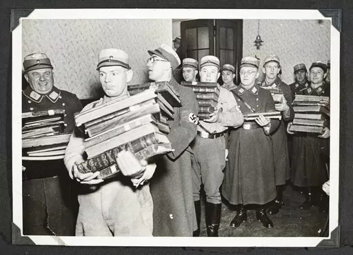This photo released by Yad Vashem, World Holocaust Remembrance Center, shows German Nazis carry Jewish books, presumably for burning, during Kristallnacht intake most likely in the town of Fuerth, Germany on Nov. 10, 1938. The photos were taken by Nazi photographers during the pogrom in the city of Nuremberg and the nearby town of Fuerth. They wound up in the possession of a Jewish American serviceman who served in Germany during World War II. His descendants,donated the album to Yad Vashem. (Ya