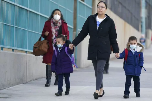 Children and their caregivers arrive for school in New York, Monday, March 7, 2022.  The Biden administration will extend for two weeks the nationwide mask requirement for public transit as it monitors an uptick in COVID-19 cases. The Centers for Disease Control and Prevention was set to extend the order, which was to expire on April 18, by two weeks to monitor for any observable increase in severe virus outcomes as cases rise in parts of the country.   (AP Photo/Seth Wenig, File)