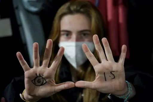 A youngster, with an eye drawn on her hand to show she is watching and 1.5 for countries to keep warming below 1.5 degrees Celsius, takes part in a Fridays for Future climate protest inside a plenary corridor at the SEC (Scottish Event Campus) venue for the COP26 U.N. Climate Summit, in Glasgow, Scotland, Nov. 10, 2021. The idea of tinkering with the air to cool Earth's ever-warming climate seems to be gaining momentum. Two new high-powered panels have started to look at the ethics and governing