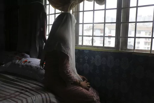 Rohingya child bride, B, age 14, sits on a bed in an apartment in Kuala Lumpur, Malaysia, on Oct. 4, 2023. B came to Malaysia in 2023 to marry an older man. Her husband wants her to get pregnant, but she says she doesn't feel ready. "I still feel like a girl." Deteriorating conditions in Myanmar and in neighboring Bangladesh’s refugee camps are driving scores of underage Rohingya girls to Malaysia for arranged marriages with Rohingya men who frequently abuse them, The Associated Press found in