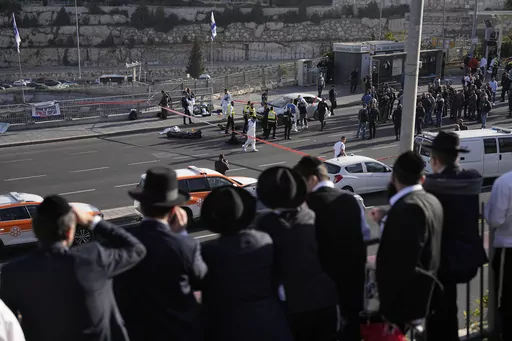 People look at Israeli police officers and volunteers from the Zaka rescue service work at the shooting attack in Jerusalem, Thursday, Nov. 30, 2023. The shooting death of an Israeli man who raced to confront Palestinian attackers has raised questions about the use of excessive force among Israeli security forces and the public. The man's shooting mirrors previous incidents where Israeli security forces or civilians have opened fire on attackers who no longer appear to pose a threat or on suspec