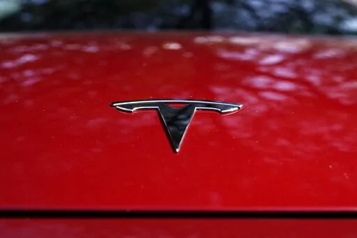 A Tesla logo is seen on a vehicle on display in Austin, Texas, Wednesday, Feb. 22, 2023. On Wednesday, March 1, Tesla executives said the company will use innovative manufacturing techniques and smaller factories to cut the cost of its next generation of vehicles by as much as half of the ones it now builds. (AP Photo/Eric Gay, File)