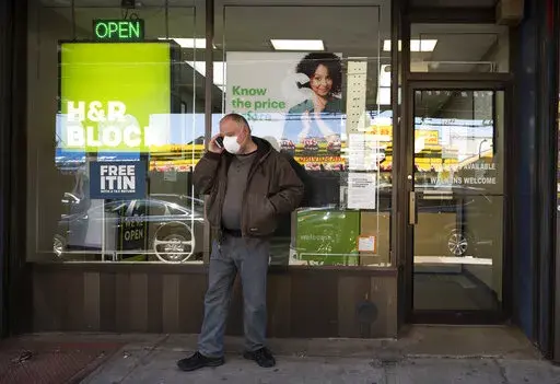 A man waits outside a H&R Block tax preparation office on Monday, April 6, 2020, in the Brooklyn borough of New York. Tax season is here again. Whether you do your taxes by yourself, go to a tax clinic or hire a professional, navigating the tax system can be complicated. (AP Photo/Mark Lennihan, File)