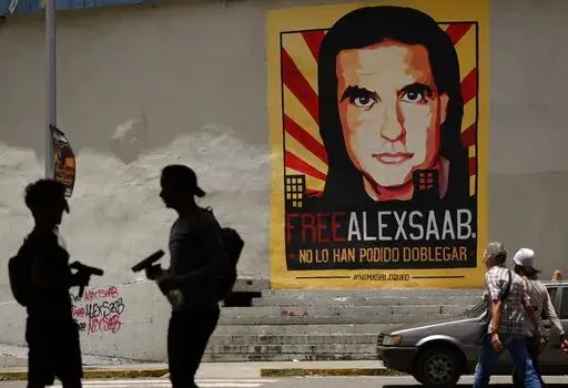 In this Sept. 9, 2021 file photo, pedestrians walk near a poster of Alex Saab that reads in Spanish "Alex Saab Free. They haven't been able to bend him," in Caracas, Venezuela. Newly unsealed court records show that the Colombian businessman linked to Venezuelan President Nicolas Maduro was secretly signed up by the D.E.A. as a cooperating source in 2018 and gave agents information about bribes he paid to Venezuelan officials. However, he was deactivated as a source after failing to meet a deadl