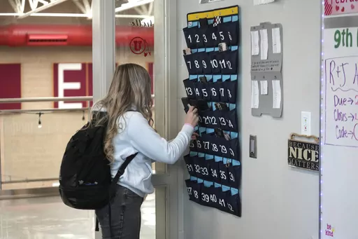 A ninth grader places her cellphone in to a phone holder as she enters class at Delta High School, Friday, Feb. 23, 2024, in Delta, Utah. Most schools have policies regulating student cellphone use at school. But the reality is kids don’t always follow the rules and schools enforce them sporadically. (AP Photo/Rick Bowmer, File)