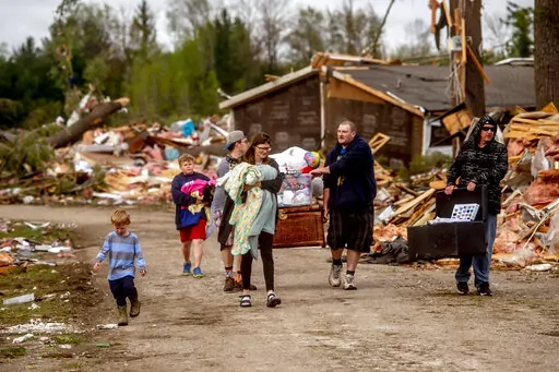 Resident Stephanie Kerwin, center, holds her baby Octavius in one arm and dog Pixie in the other as she and her family carry what they could salvage from her home in Nottingham Forest Mobile Home Park, Saturday, May 21, 2022, in Gaylord, Mich., following a tornado the day before. "This morning is when it first hit me...I could have lost people that I really love. I am so grateful," Kerwin said. (Jake May/MLive.com/The Flint Journal via AP)